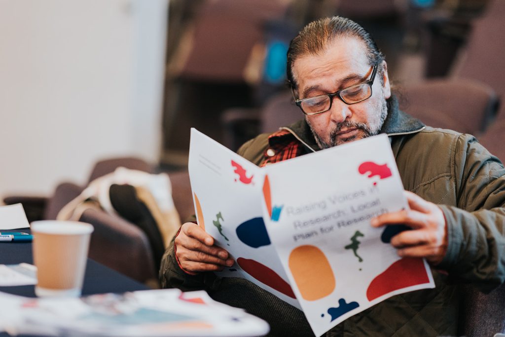 Man Reading Raising Voices in Research Local Plan for Research Document at Conference